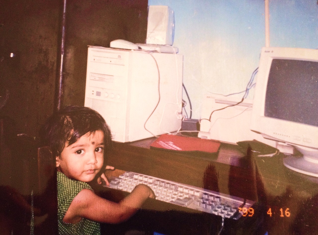 A child at a desk stacked with old computers